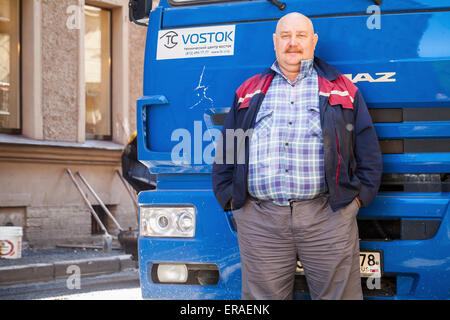 Saint-Petersburg, Russia - May 30, 2015: Senior positive truck driver with mustaches stands near his blue Kamaz lorry cabin Stock Photo