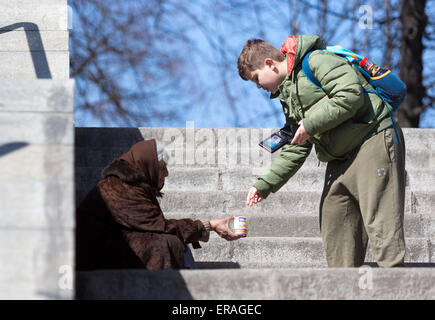 Sofia, Bulgaria - March 17, 2015: A boy is giving money to a homeless female begger who is begging at the subway underpass stair Stock Photo