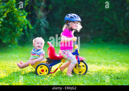 Children riding a bike. Kids enjoying a bicycle ride. Little preschooler girl and baby boy, brother and sister Stock Photo