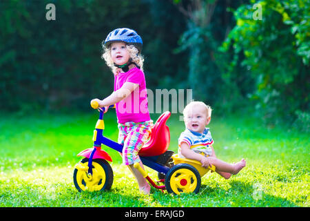 Children riding a bike. Kids enjoying a bicycle ride. Little preschooler girl and baby boy, brother and sister Stock Photo