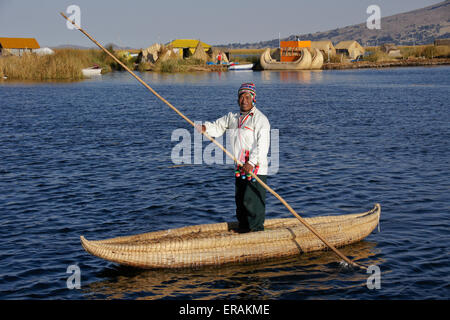 Uros Indian man in tortora reed boat near floating island, Lake Titicaca, Puno, Peru