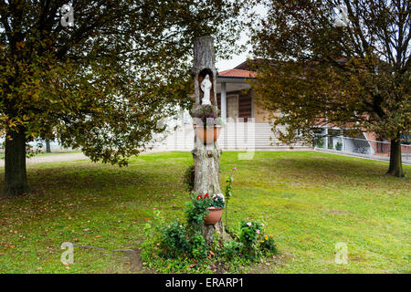 Statue of the Our Lady in hollow trunk the garden in front of the church dedicated to the Blessed Virgin Mary in the village of Santa Maria in Fabriago near Ravenna in the countryside of Emilia Romagna in Northern Italy. Stock Photo