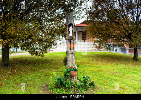 Statue of the Our Lady in hollow trunk the garden in front of the church dedicated to the Blessed Virgin Mary in the village of Santa Maria in Fabriago near Ravenna in the countryside of Emilia Romagna in Northern Italy. Stock Photo