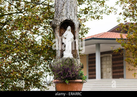 Statue of the Our Lady in hollow trunk the garden in front of the church dedicated to the Blessed Virgin Mary in the village of Santa Maria in Fabriago near Ravenna in the countryside of Emilia Romagna in Northern Italy. Stock Photo