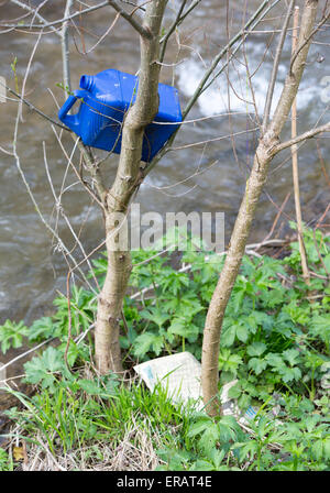 Plastic bottle trash is thrown in the branches of a tree near a river. Stock Photo