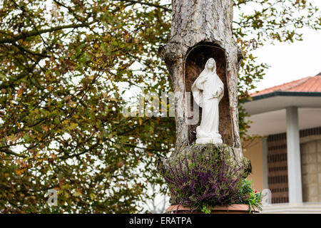 Statue of the Our Lady in hollow trunk the garden in front of the church dedicated to the Blessed Virgin Mary in the village of Santa Maria in Fabriago near Ravenna in the countryside of Emilia Romagna in Northern Italy. Stock Photo