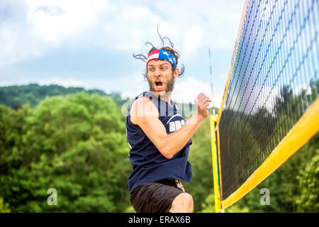 Natural looking beachvolley ball player with stars and stripes bandana celebrates  his game success emotional. Stock Photo
