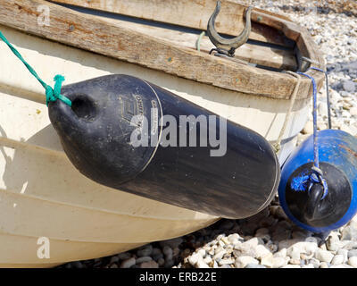 Black and blue fenders on the side of a small fibreglass rowing boat. Stock Photo