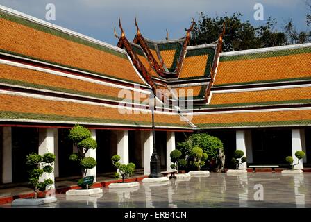 Bangkok, Thailand:  Topiary trees, cloister gallery buildings with tiled orange roofs, at Wat Suthat Stock Photo