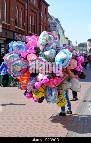 Ipswich town centre market stalls area with street seller holding large cluster of gas filled balloons Stock Photo