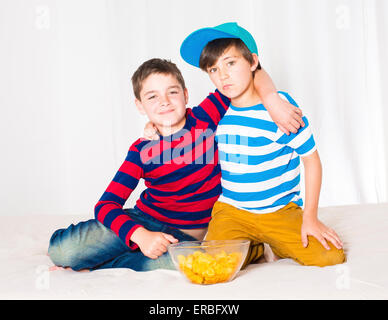 two kids in bed eating potato chips Stock Photo