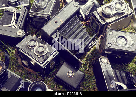 Collection of old vintage retro film analogue cameras lying on green grass lawn background Stock Photo