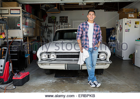 Portrait smiling young man with vintage car garage