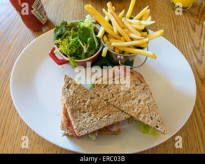 Café lunch a two- layer Club sandwich in brown bread with bacon lettuce tomato chicken and mayo with salad and French Fries Stock Photo