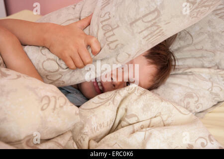 Baby girl pulling up pants on bed stock photo