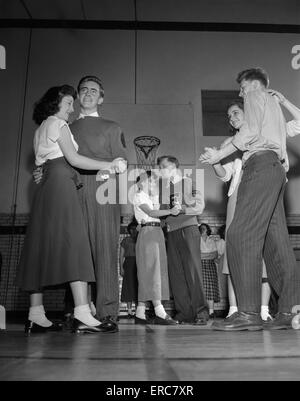 1940s 1950s TEENAGE BOYS AND GIRLS DANCING SLOW DANCE AT PARTY IN HIGH SCHOOL GYMNASIUM Stock Photo