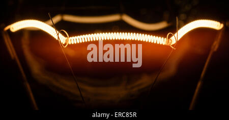 Filament of an incandescent electric light bulb, turned on. Stock Photo