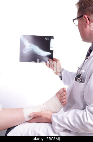 The doctor examines an X-ray picture , while the patient's sprained foot resting in his hand Stock Photo