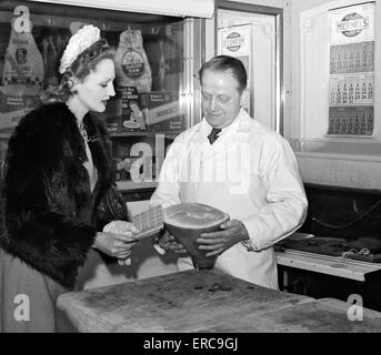 1940s WOMAN CUSTOMER SHOWING HER RATION POINT BOOK TO BUTCHER AT MEAT MARKET NEW YORK CITY NEW YORK USA Stock Photo