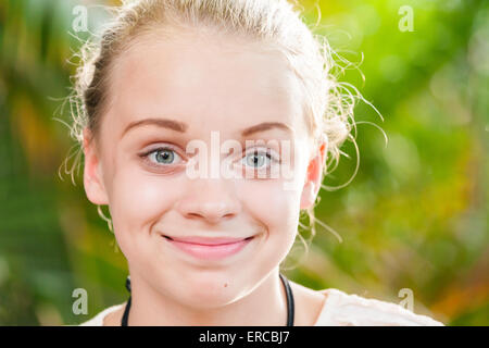 Closeup outdoor portrait of beautiful happy blond Caucasian teenage girl in a summer park Stock Photo