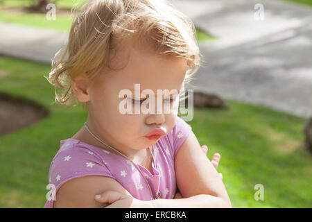 Outdoor closeup portrait, funny Caucasian blond baby girl resentfully pouts Stock Photo