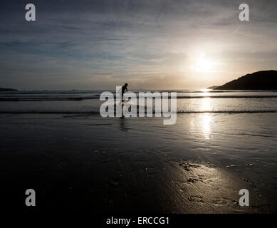 A young boy skimboarding at sunset on Whitesands Beach in St Davids, Pembrokeshire Wales Stock Photo