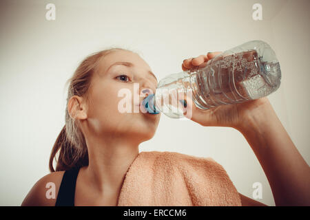 Teen girl drinks bottled water after exercising, vignette toned Stock Photo