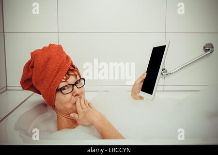Confused woman in bathtub with tablet computers, retro style Stock Photo
