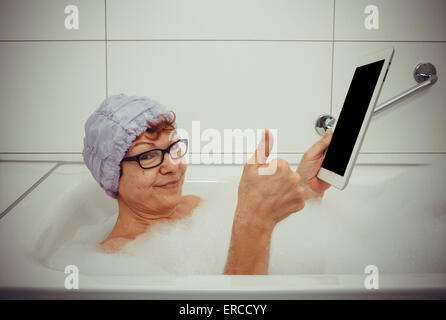 Woman in bathtub with tablet computers make ok, retro style Stock Photo