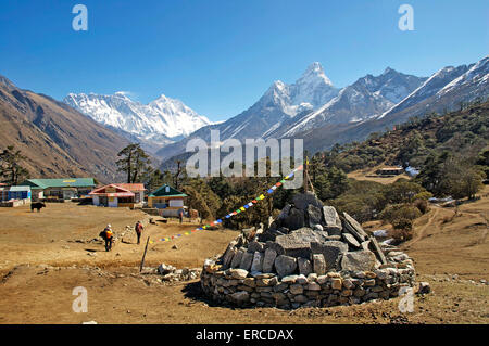 Mani stones and prayer flags in the centre of Tengboche, Nepal.  The twin peaks of Ama Dablam dominate the skyline. Stock Photo