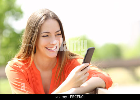 Happy girl using a smart phone in summer in a park Stock Photo