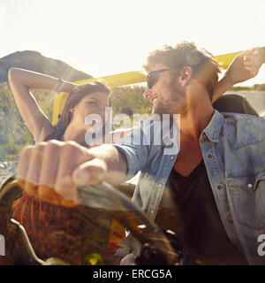 Happy young man and woman in a car enjoying a road trip on a summer day. Couple out on a drive in a open car.