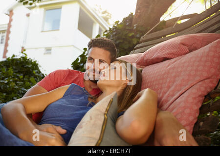 Appreciative and loving young couple relaxing on a hammock together. Young man looking away and woman with her eyes closed in th Stock Photo