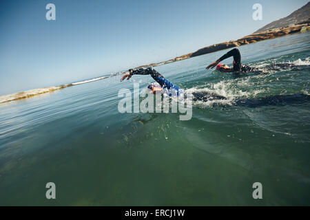 Athletes swimming on triathletic competition. Competitors swims freestyle in the water. Stock Photo