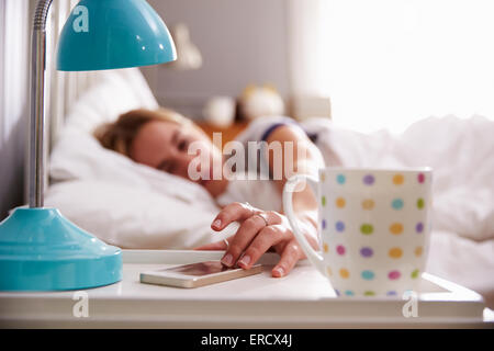 Sleeping Woman Being Woken By Mobile Phone In Bedroom Stock Photo