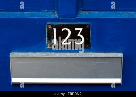 Documentary close up image of house number 123 on a bright blue door with metal letterbox in view Stock Photo