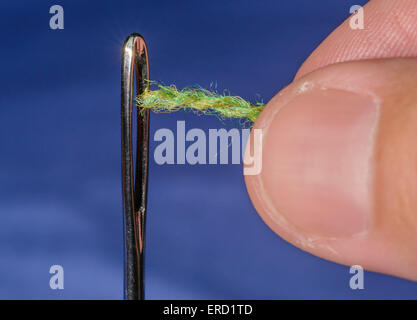 Threading.needle Closeup of a man's fingers threading through the eye of a darning needle. Stock Photo