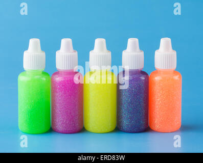 Glitter glue in bright colors for crafts, on blue background Stock Photo