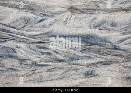 Abstract background of wet sand texture formed by flowing water on beach Stock Photo