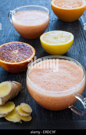 Fresh citrus and ginger smoothies with fruit slices on rustic wooden background Stock Photo