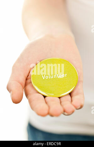 Closeup on female hand holding green volunteer button Stock Photo