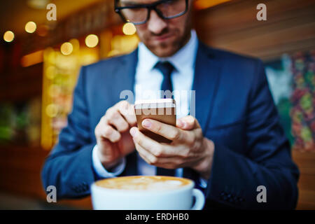 Young businessman writing sms in cafe Stock Photo
