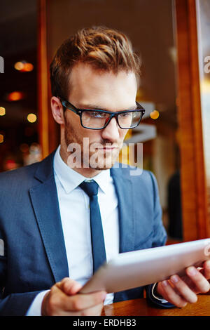 Serious businessman with touchpad networking in cafe Stock Photo