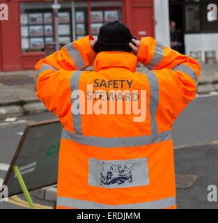 Safety steward at a 10 kilometer running event wearing an orange high vis jacket Stock Photo