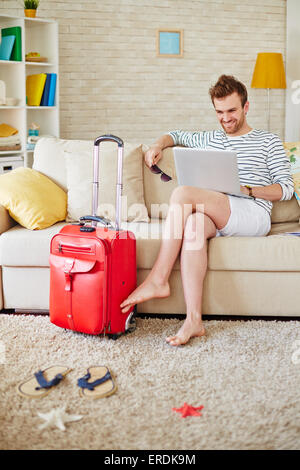 Young man browsing in the net while choosing tour Stock Photo
