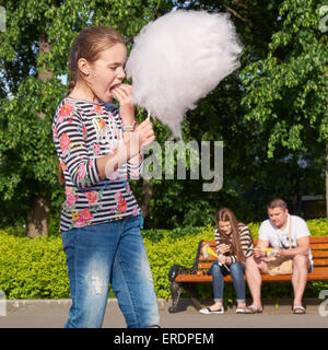 young girl eating cotton candy in the city park Stock Photo