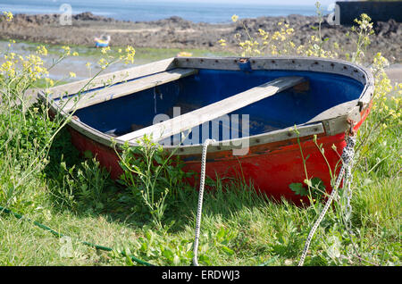 Blue and red wooden rowing boat abandoned on a beach in Guernsey