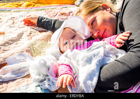 Close up of Caucasian mother and baby girl laying on blanket Stock Photo