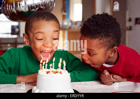 Black boys blowing out cake candles at party Stock Photo