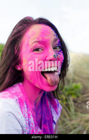Caucasian woman splattered with paint powder with tongue out Stock Photo